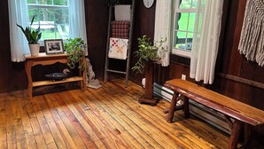 A cozy room with wooden flooring, a wooden bench, a ladder, a quilted table, and potted plants. - Original log cabin on 3 private acres (Boswell)