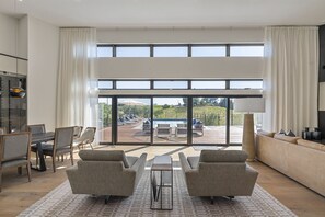 A spacious living room with a large sliding glass door leading to an outdoor patio with a pool and lounge chairs.