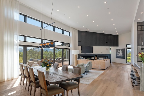 A spacious living area with a dining table, sofas, and a fireplace.