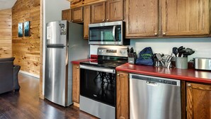Una cucina con rivestimenti in legno, elettrodomestici in acciaio inossidabile e un piano di lavoro rosso.