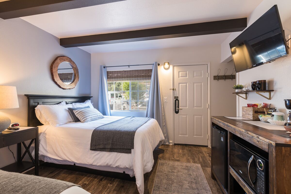 A bedroom with a bed, bedside table, and a TV mounted on the wall.