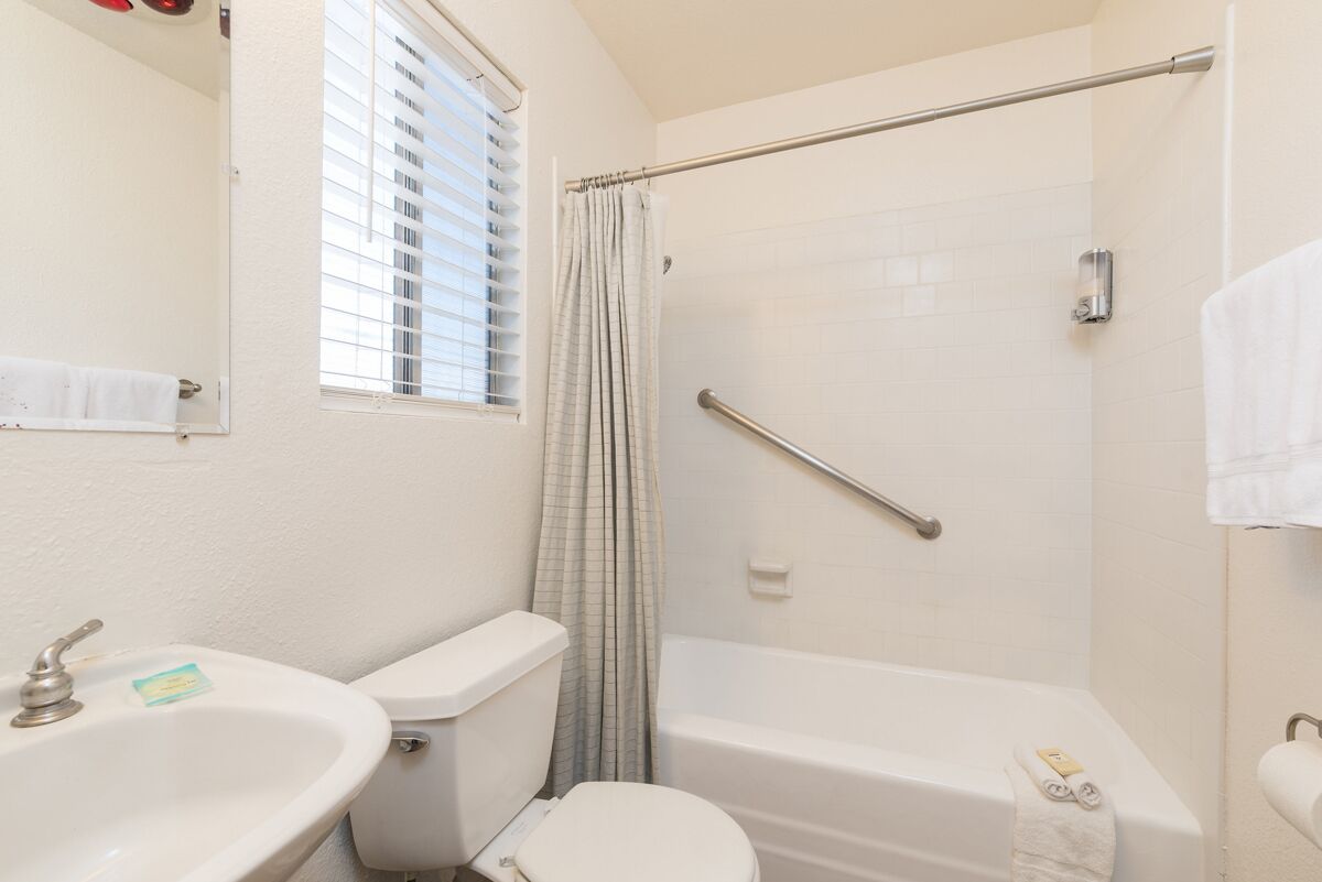 A bathroom with a toilet, sink, bathtub, and shower.