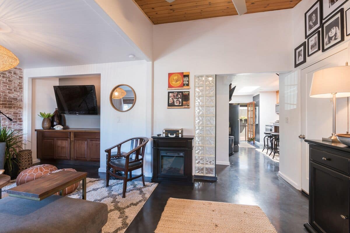 A modern living room with a fireplace, a television, and a dining area in the background.