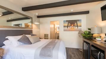 A bedroom with a bed, bedside table, lamp, and a large mirror.