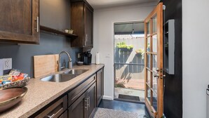 A kitchen with dark wooden cabinets, a granite countertop, a sink, and a sliding glass door leading to a patio.
