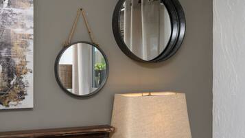 Two round mirrors on a wall, a lamp, and a piece of abstract art.