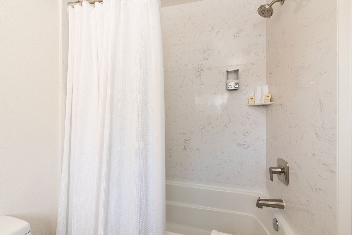 Een badkamer met een douche, toilet en een marmeren wand.