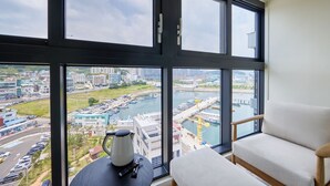 A room with large windows offering a view of a harbor and cityscape. - Shift Door Residence Hari (Busan)