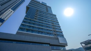 A tall, modern building with a clear sky and sunlight. - Shift Door Residence Hari (Busan)