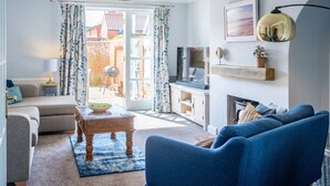 A living room with a sofa, a coffee table, a TV, and a fireplace. - Birch Cottage, Northrepps, Norfolk (Northrepps)