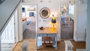 A hallway with a wooden bench, a table with a lamp, and a mirror on the wall. - Birch Cottage, Northrepps, Norfolk (Northrepps)
