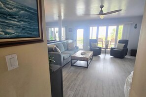 A spacious living area with a sofa, armchairs, a coffee table, and a ceiling fan.