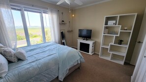 Ein Schlafzimmer mit Bett, Fernseher, Bücherregal und Blick ins Freie.