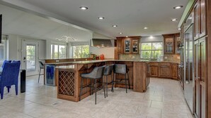 Una cocina amplia con una isla grande, taburetes de bar y armarios de madera.