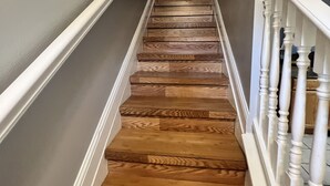 A wooden staircase with white balusters and a handrail, leading to a landing with a framed sign. - Beach Life Condo 135. Pools! Beach! Casinos! FUN! (Biloxi)
