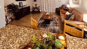 A living room with a sofa, coffee table, TV, and plants. - Beach Life Condo 135. Pools! Beach! Casinos! FUN! (Biloxi)
