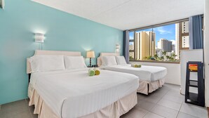 Une chambre d’hôtel avec deux lits, une grande fenêtre donnant sur la ville et un petit balcon.