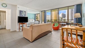Un salon moderne avec un canapé, un téléviseur et un coin repas offrant une vue sur la ville.