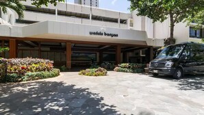 Un bâtiment sur lequel on peut lire l’inscription « walkk banyan », avec un fourgon Mercedes-Benz garé devant.