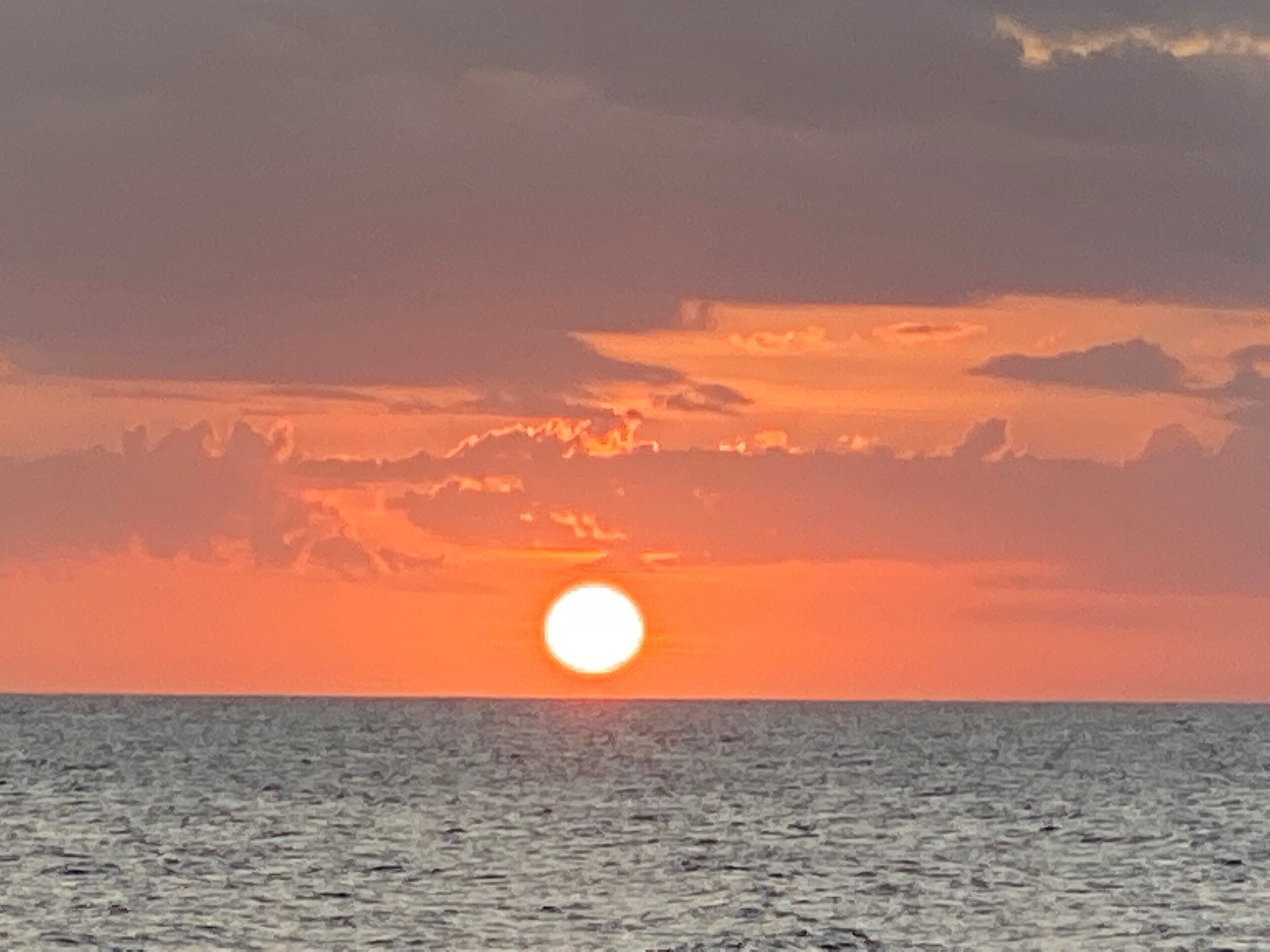 A sunset over the ocean with a clear sky.