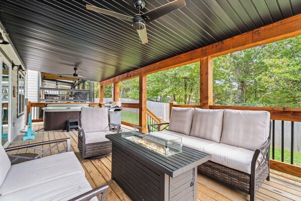 Una terraza exterior con sofá, sillones, una chimenea y un ventilador de techo.