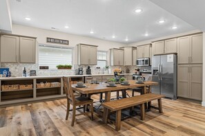 A modern kitchen with wooden flooring, beige cabinets, and a central island.