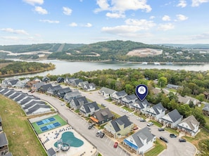 A residential area with houses, a swimming pool, and a lake in the background.