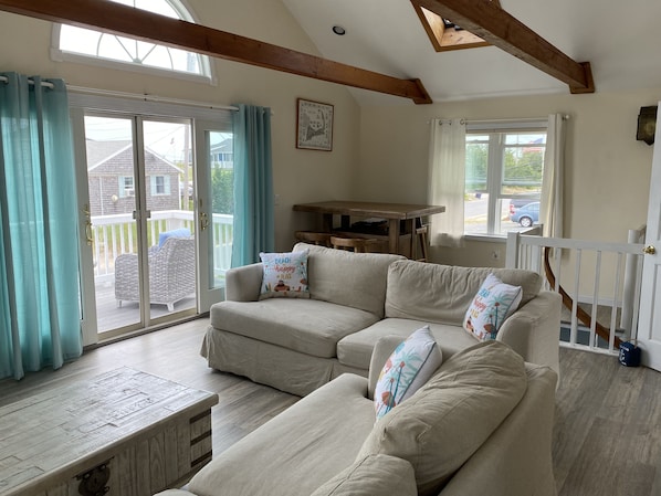Una sala de estar acogedora con un sofá color beige, una mesa de centro de madera y vistas al porche exterior.