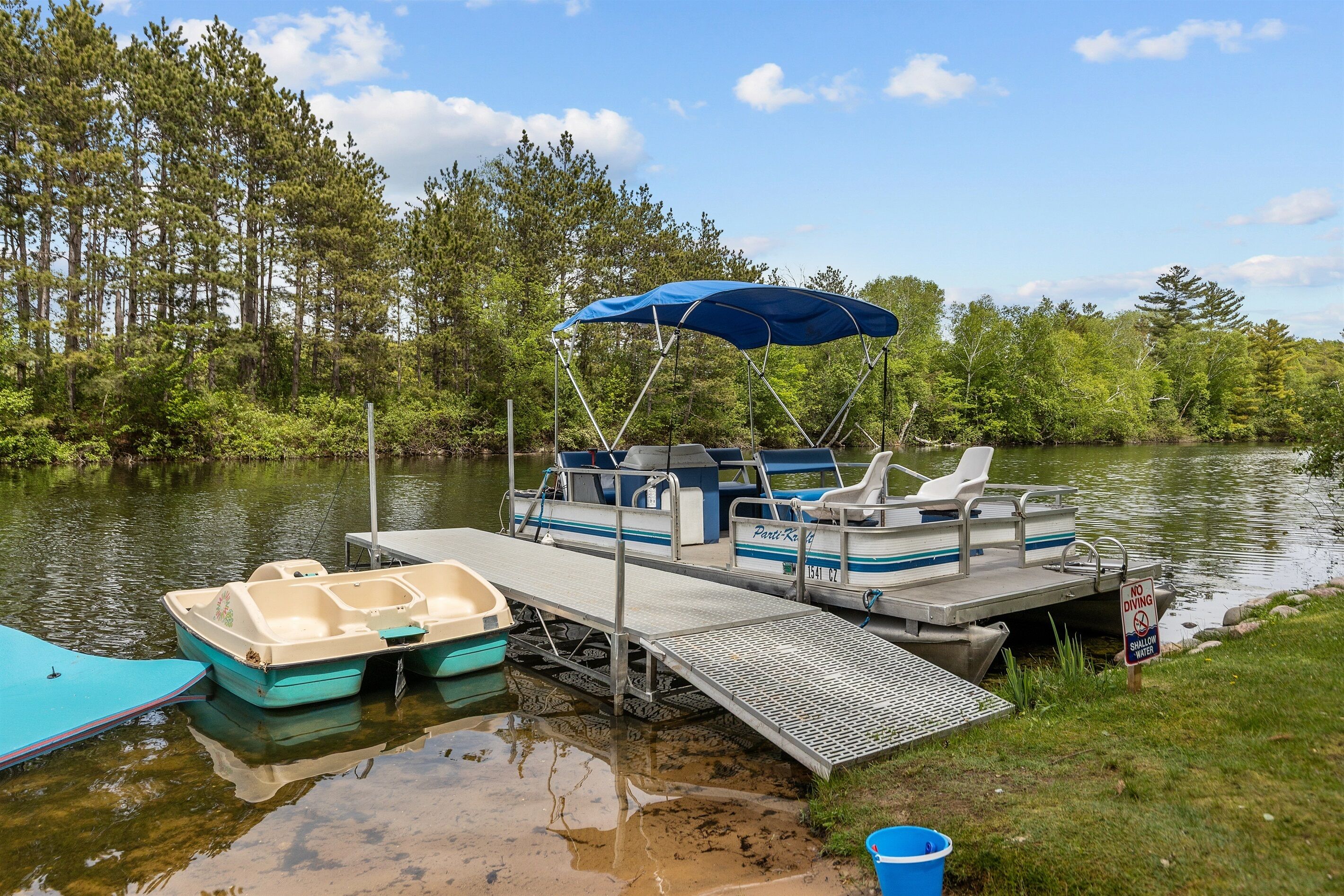 A dock with a covered boat, a small boat, and a 'NO DIVING' sign.