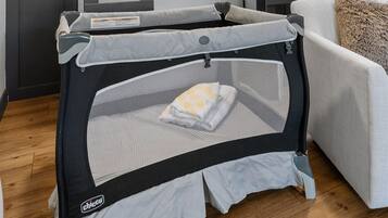 A bunk bed with a safety rail, a white couch, and a window with a view of trees.
