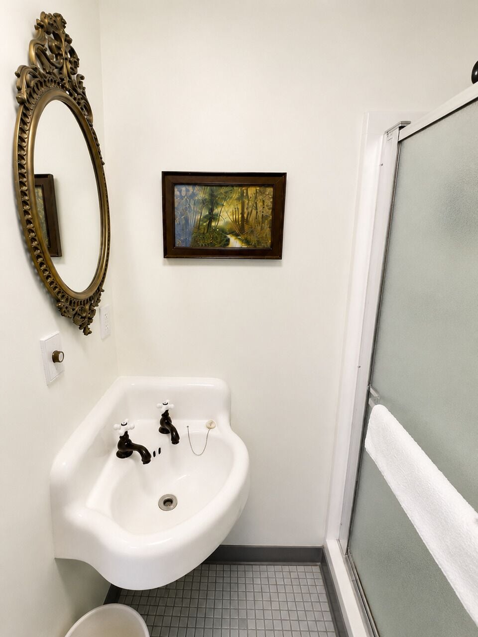 Une salle de bain avec un lavabo blanc, un tableau encadré et un miroir décoratif.
