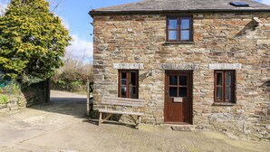 A stone cottage with a wooden bench outside, a door, and a window. - Keepers Cottage (Liskeard)