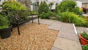 A garden area with a bench, potted plants, and a stone pathway. - Flat 6 (Falmouth)