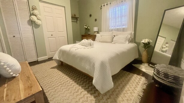 Une chambre bien rangée, avec un lit, une table de chevet, un miroir et une armoire.