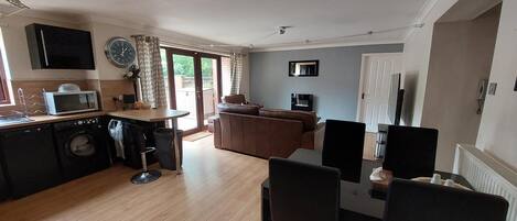 Ett kompakt bostadsutrymme med kök, matplats och en sittgrupp.