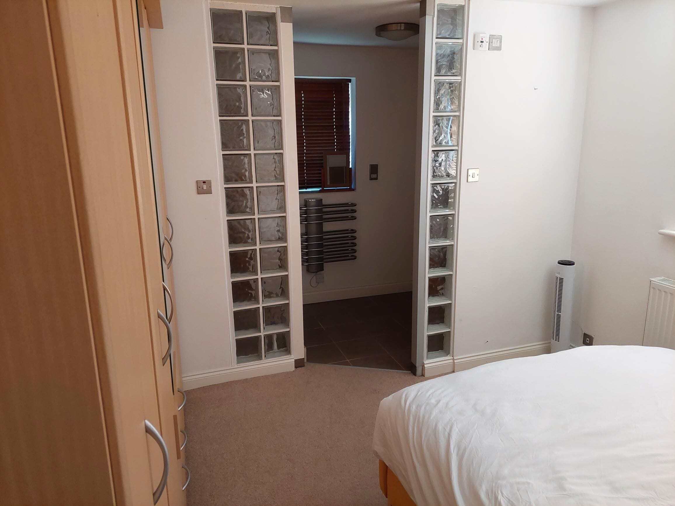 Un dormitorio con cama, armario y estantería empotrada con puertas de cristal.