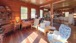 Een gezellig chaletinterieur met houten vloeren, een eethoek en een keuken die door een open deur zichtbaar is.