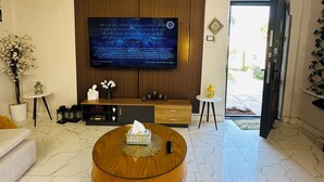 A modern living room with a large flat-screen TV, a round coffee table, a sofa, and a small side table with a lamp. - privet villa close to the beach (Hurghada)