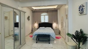 A bedroom with a bed, bedside tables, a wardrobe, a ceiling light fixture, and a potted plant. - privet villa close to the beach (Hurghada)
