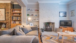 Een gezellige woonkamer met een open haard, een boekenkast, een bank en een televisie.
