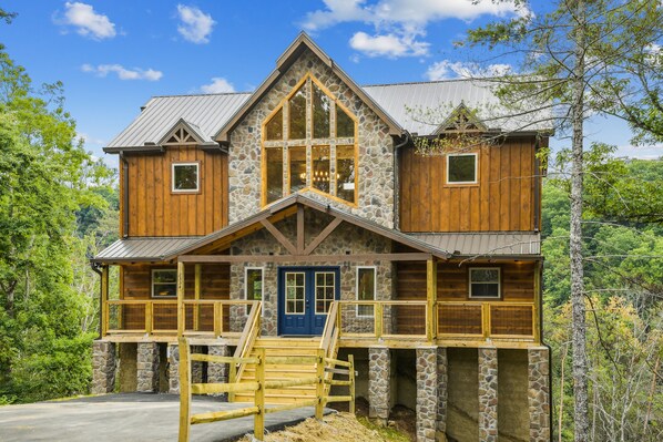Eine zweistöckige Blockhütte mit Natursteinfundament, Holzfassade und einer blauen Haustür.