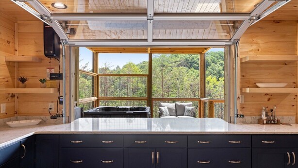 A modern kitchen with a large window, wooden cabinets, and a marble countertop. - Stargazer Chalet 5 Bedroom Cabin by RedAwning (Sevierville)