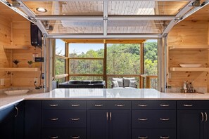 A modern kitchen with a large window, wooden cabinets, and a marble countertop. - Stargazer Chalet 5 Bedroom Cabin by RedAwning (Sevierville)