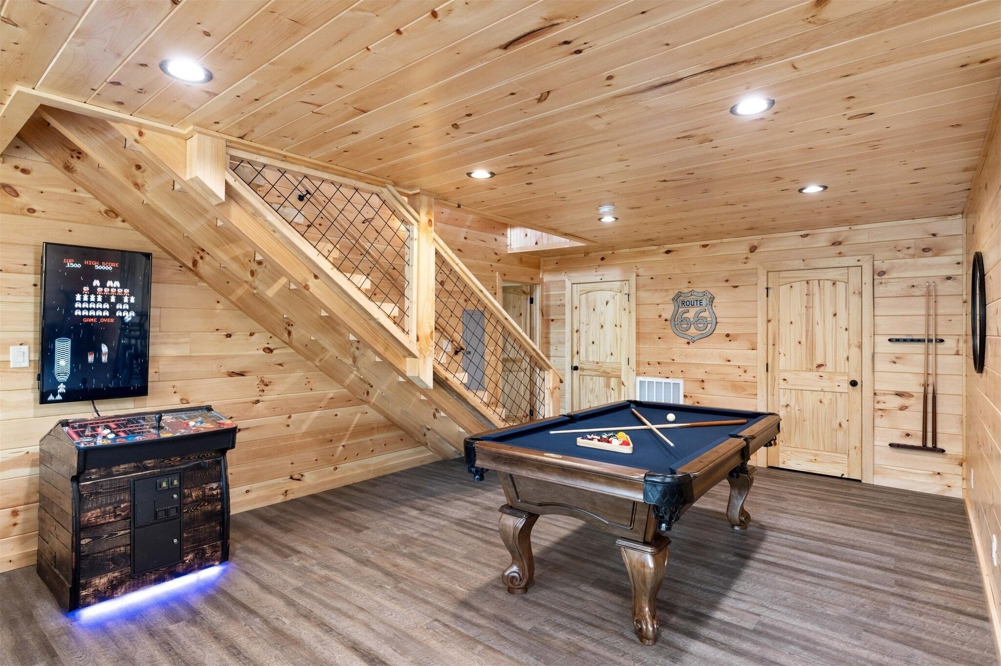 Un intérieur en bois avec une table de billard, un escalier et un juke-box.