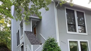 A two-story house with a front porch and a small staircase.