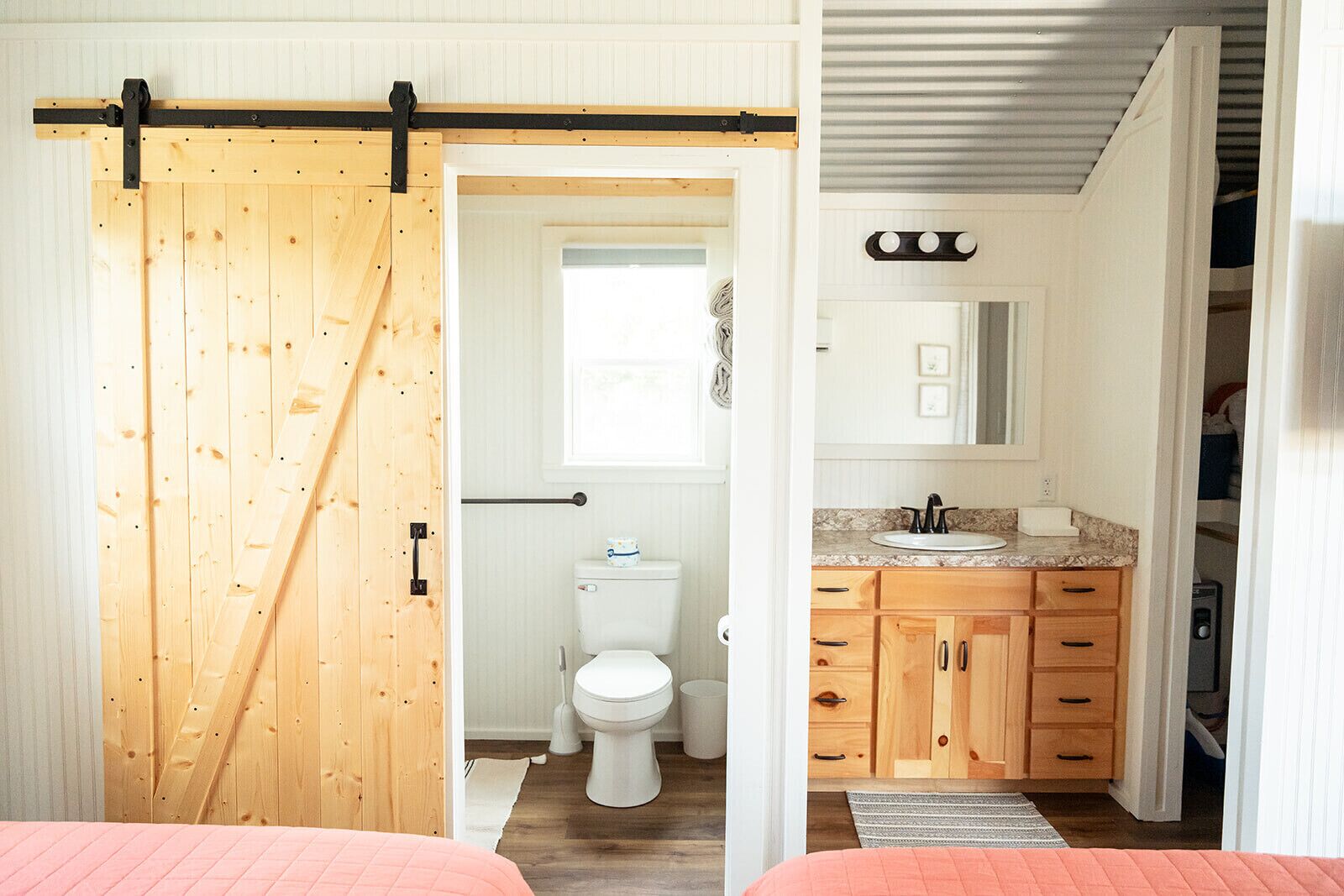 Una habitación con puerta corredera de madera, un inodoro, un lavabo y armarios de madera.