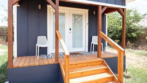 Eine überdachte Veranda mit Holzstufen und zwei weißen Stühlen.