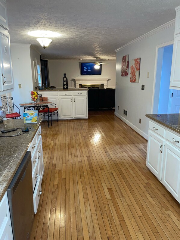 A spacious kitchen with wooden flooring, white cabinetry, and a built-in oven.