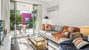 A modern living room with a sofa, coffee table, and a balcony with outdoor furniture. - Home away from Home! 2Bed/1Bath/Car/Pool~2kms CBD (Fortitude Valley)