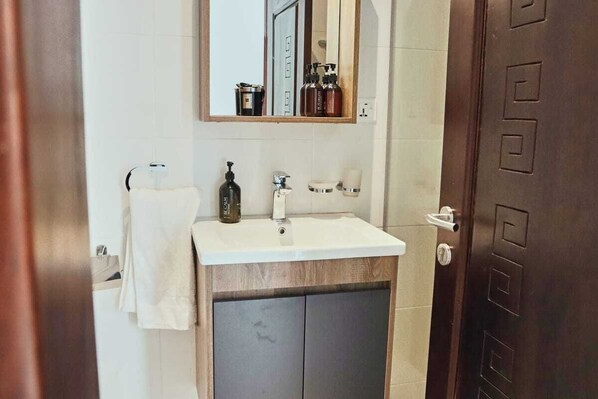 A bathroom with a white sink, a mirror, and a wooden cabinet below.